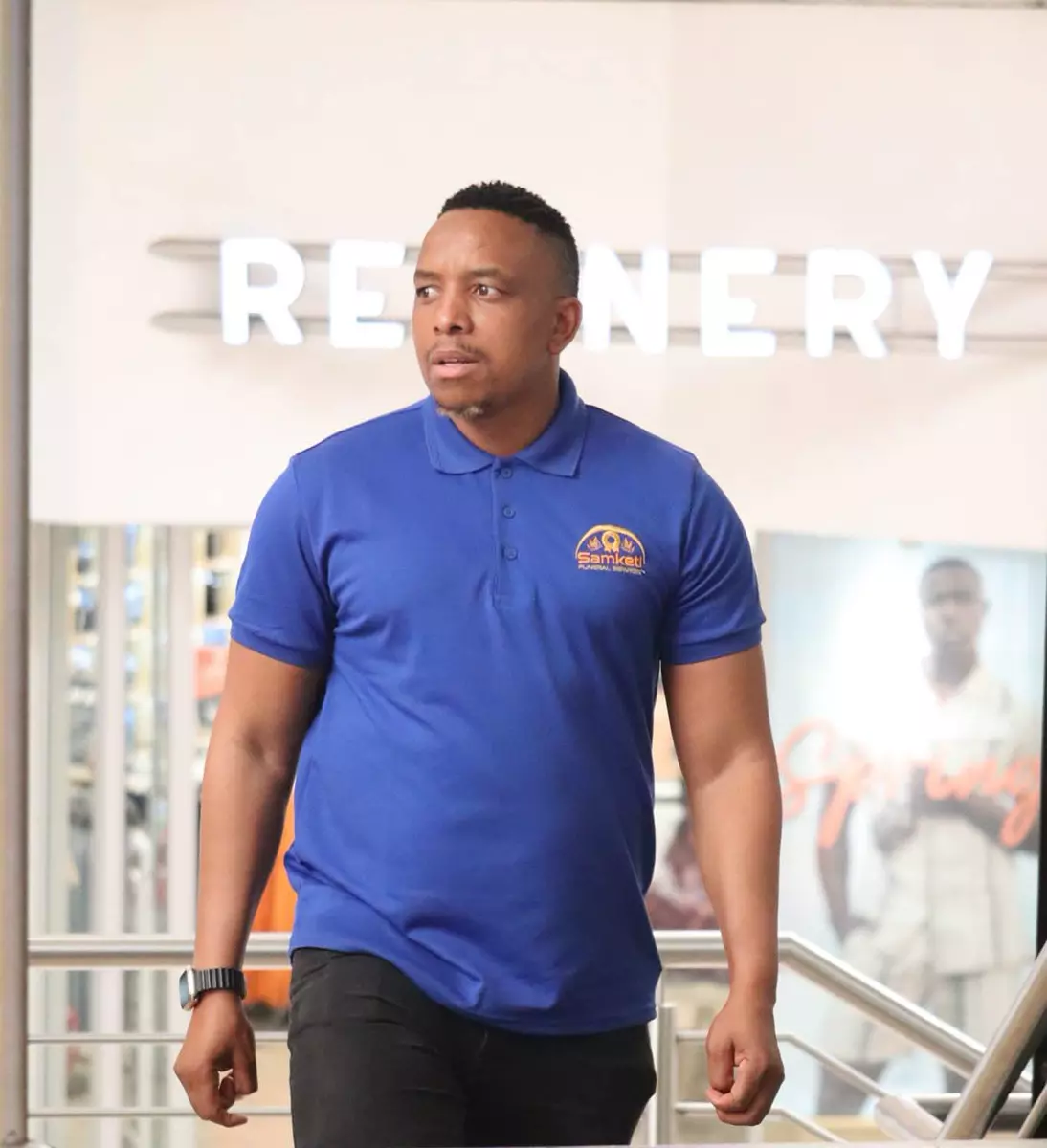 A man wearing a Samketi Funeral Services branded polo shirt standing indoors